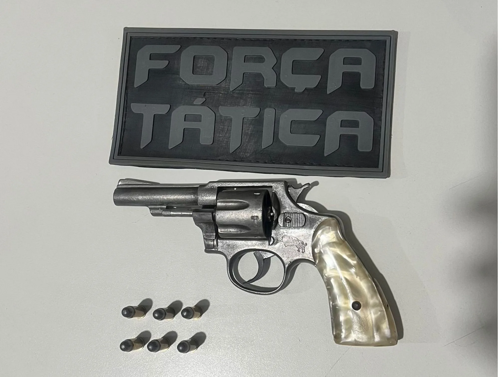 Arma em cima da mesa com escudo da Força Tática da Polícia Militar do Piauí